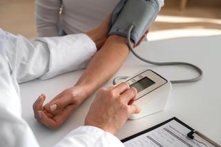 Doctor  measuring patient's blood pressure on medical device as a part of heart check-up.